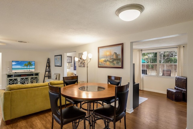 dining space featuring baseboards, a textured ceiling, visible vents, and dark wood-type flooring