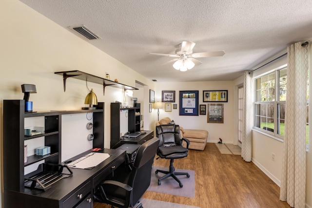 office area with visible vents, a ceiling fan, a textured ceiling, wood finished floors, and baseboards