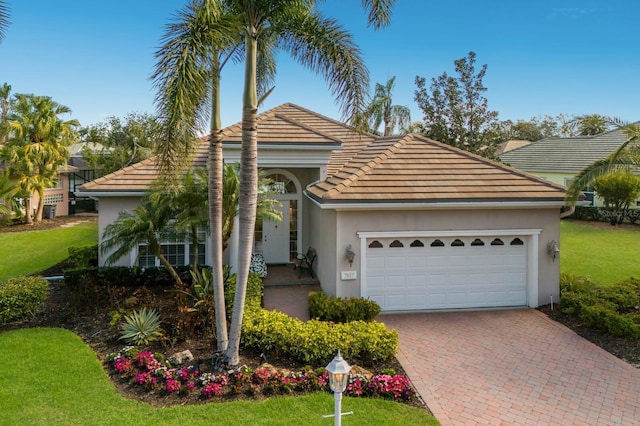 view of front of property featuring decorative driveway, stucco siding, an attached garage, a front yard, and a tiled roof