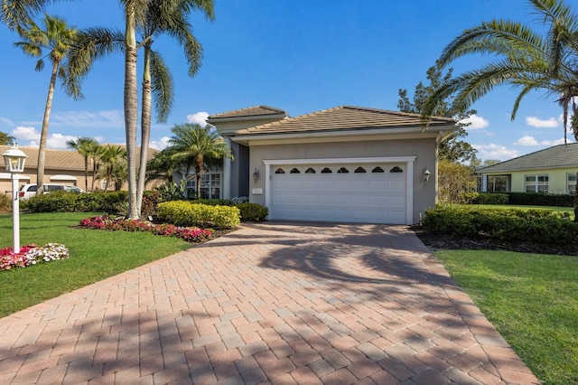 view of front of home featuring a front lawn, decorative driveway, an attached garage, and stucco siding