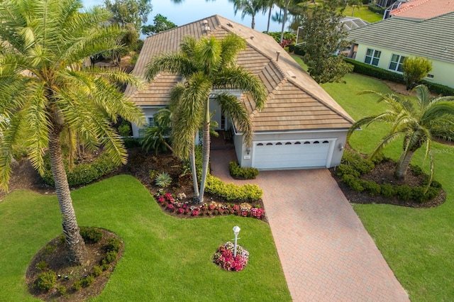 view of front of property featuring a front lawn, decorative driveway, an attached garage, and stucco siding