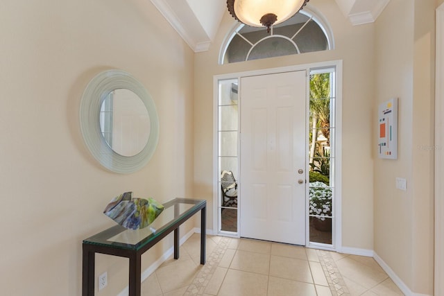 foyer entrance featuring lofted ceiling, baseboards, ornamental molding, and light tile patterned flooring