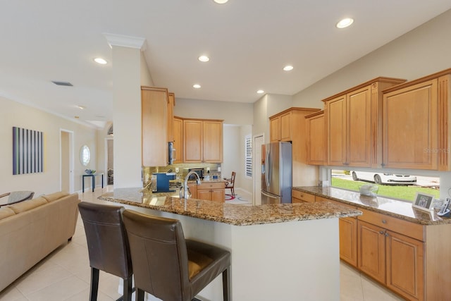 kitchen featuring stone counters, stainless steel appliances, visible vents, ornamental molding, and a peninsula