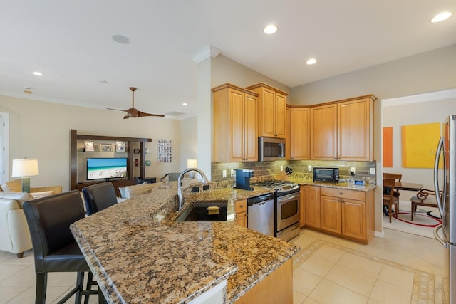 kitchen with stainless steel appliances, a sink, a peninsula, and decorative backsplash