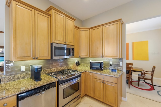 kitchen featuring light stone countertops, stainless steel appliances, backsplash, and light tile patterned flooring