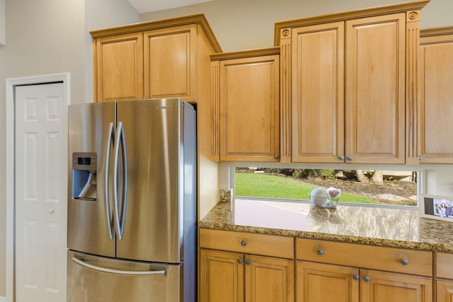 kitchen featuring light stone counters, stainless steel refrigerator with ice dispenser, and brown cabinets