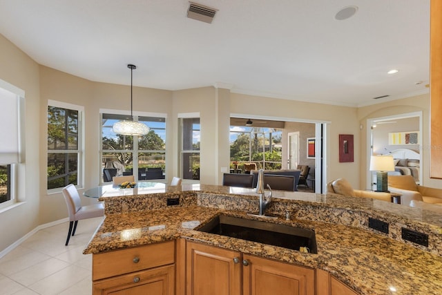 kitchen with light stone counters, light tile patterned flooring, a sink, visible vents, and hanging light fixtures