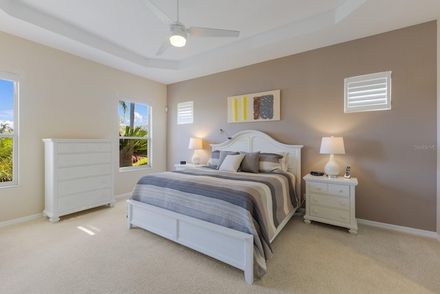 bedroom with baseboards, a tray ceiling, ceiling fan, and light colored carpet