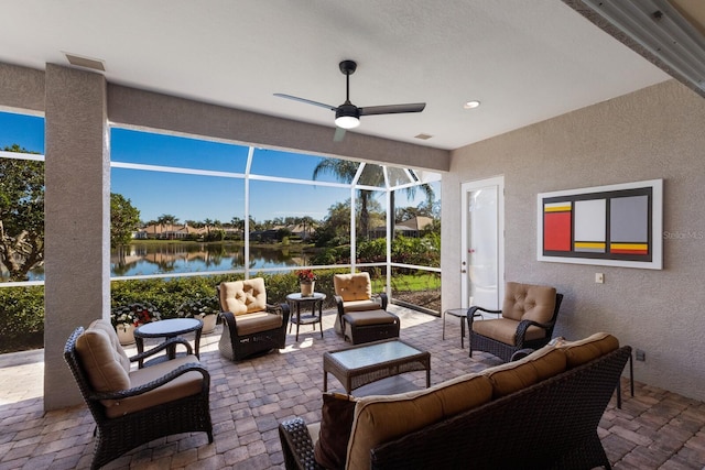 view of patio with a water view, glass enclosure, outdoor lounge area, and a ceiling fan