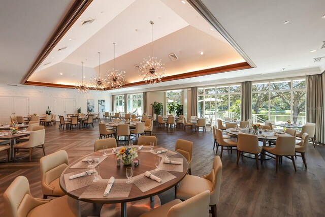 dining space with visible vents, a chandelier, a raised ceiling, and a wealth of natural light