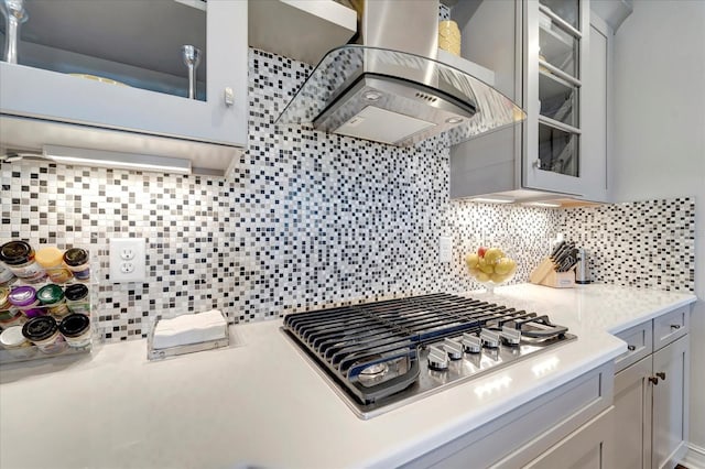 kitchen with stainless steel gas cooktop, light countertops, island exhaust hood, and glass insert cabinets