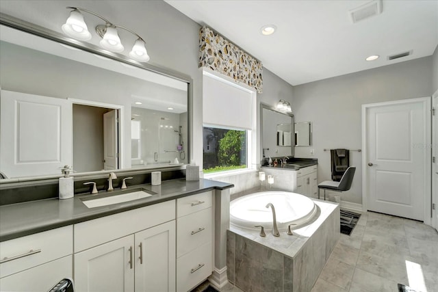 full bathroom featuring a bath, two vanities, a sink, and visible vents