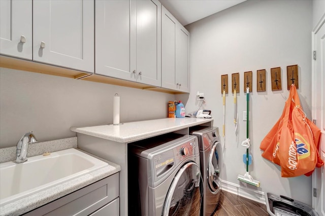 washroom with dark wood finished floors, independent washer and dryer, a sink, and cabinet space