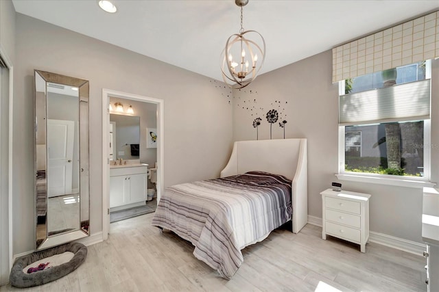 bedroom with a chandelier, light wood-type flooring, connected bathroom, and baseboards