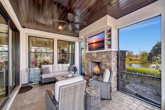 sunroom featuring a ceiling fan, wooden ceiling, and an outdoor stone fireplace