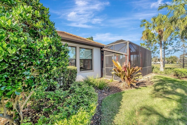 view of property exterior with a lanai, stucco siding, and a yard