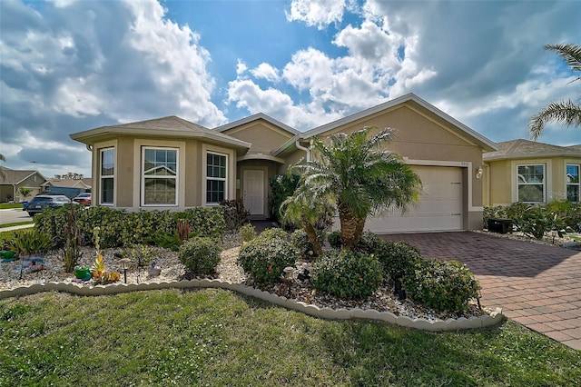 ranch-style home with a garage, decorative driveway, and stucco siding