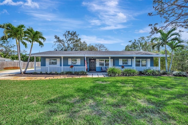 ranch-style home featuring covered porch, fence, and a front yard