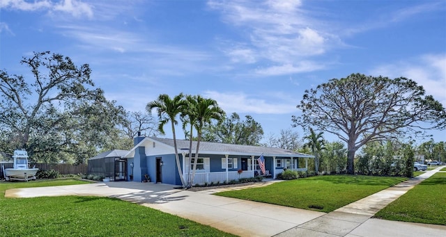 ranch-style home with a front yard, concrete driveway, and fence