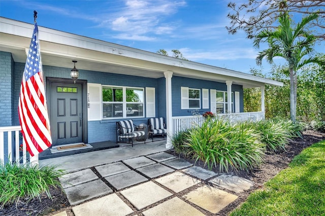 property entrance featuring covered porch and brick siding