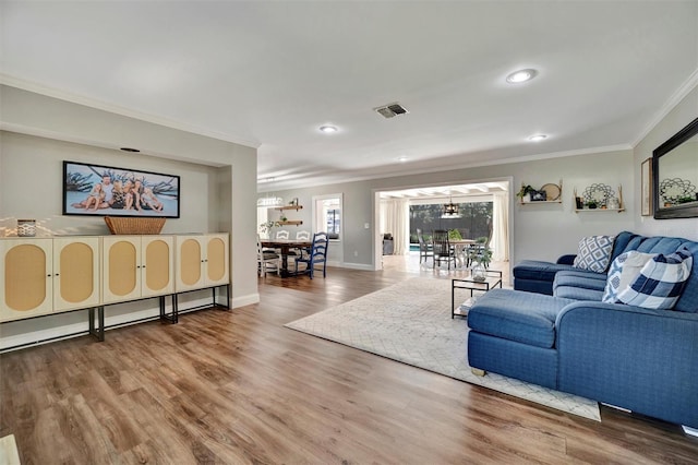 living room with crown molding, visible vents, an inviting chandelier, wood finished floors, and baseboards