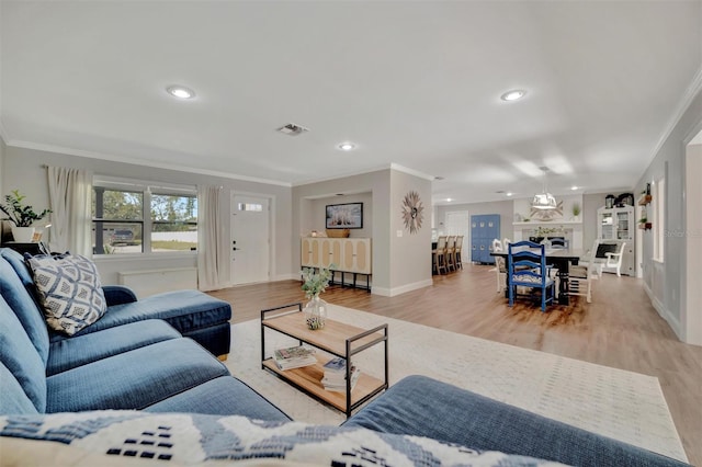 living area with visible vents, crown molding, and wood finished floors