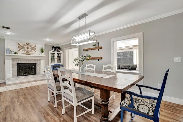 dining area featuring light wood finished floors, ornamental molding, visible vents, and baseboards