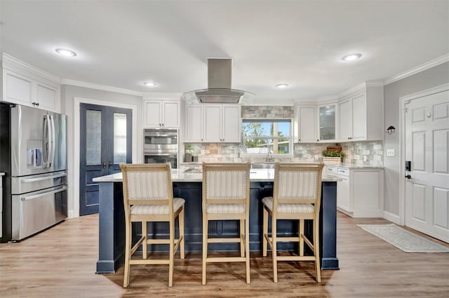 kitchen with stainless steel appliances, white cabinets, crown molding, and island exhaust hood