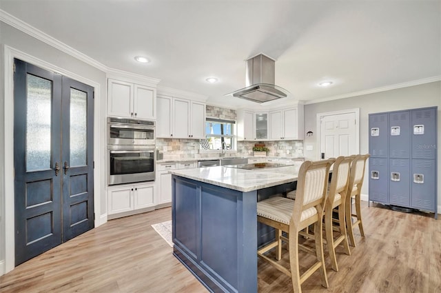 kitchen with island exhaust hood, crown molding, black electric stovetop, double oven, and white cabinetry