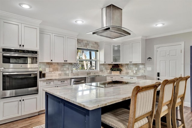 kitchen with stainless steel appliances, ornamental molding, white cabinets, and island range hood