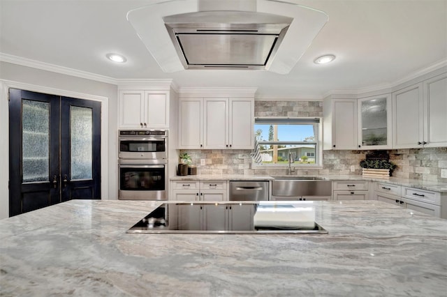 kitchen with light stone counters, decorative backsplash, stainless steel appliances, and a sink