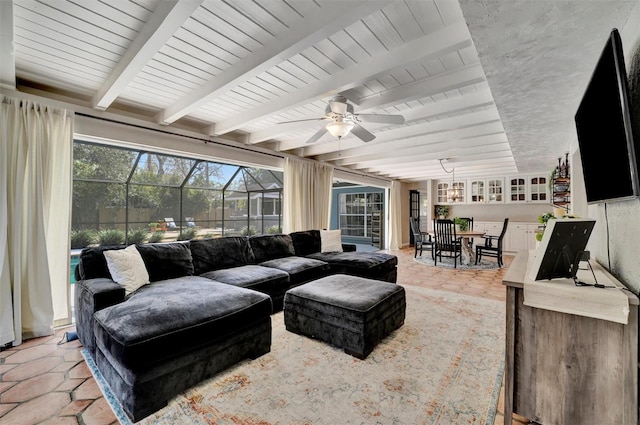 living room with a sunroom, ceiling fan, and beam ceiling