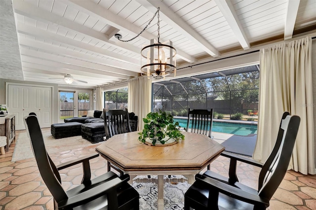 dining space with a ceiling fan, a sunroom, and beamed ceiling