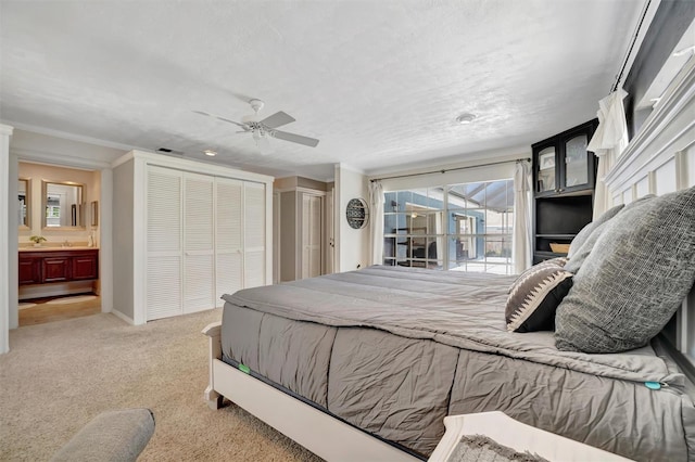 bedroom featuring visible vents, a ceiling fan, ensuite bathroom, carpet floors, and multiple closets