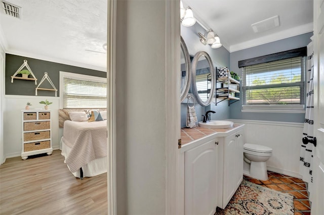 ensuite bathroom with a wealth of natural light, visible vents, toilet, and ensuite bath