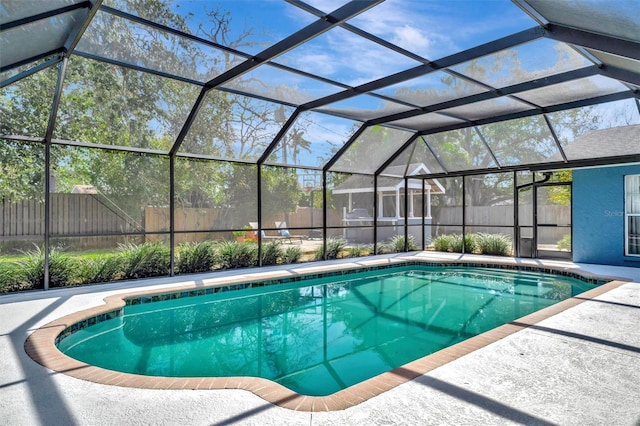 view of swimming pool featuring glass enclosure, a patio area, a fenced backyard, and a fenced in pool