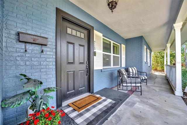 property entrance with a porch and brick siding