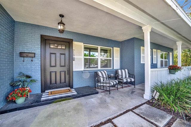 entrance to property with covered porch and brick siding