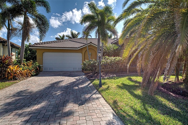 mediterranean / spanish house featuring decorative driveway, an attached garage, a tile roof, and stucco siding