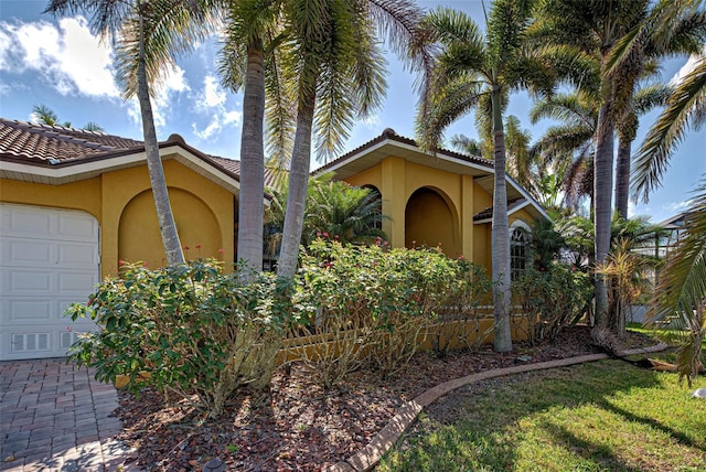 mediterranean / spanish house featuring a garage, a tile roof, and stucco siding