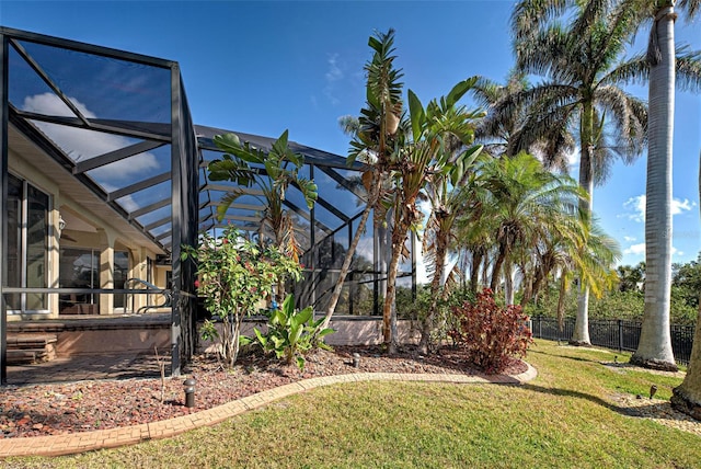 view of yard with glass enclosure and fence