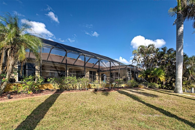 back of house featuring glass enclosure and a lawn