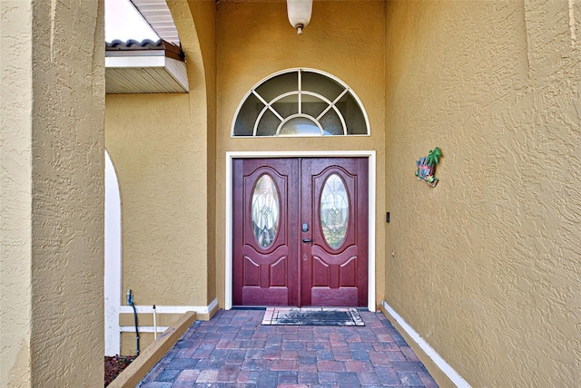 entrance to property featuring a tile roof and stucco siding