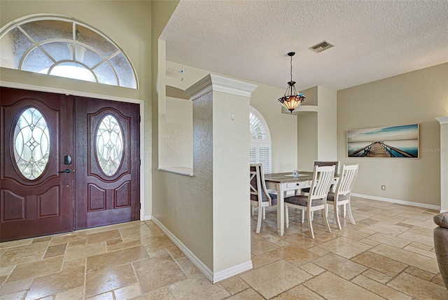 foyer entrance featuring baseboards, visible vents, stone tile floors, and a healthy amount of sunlight