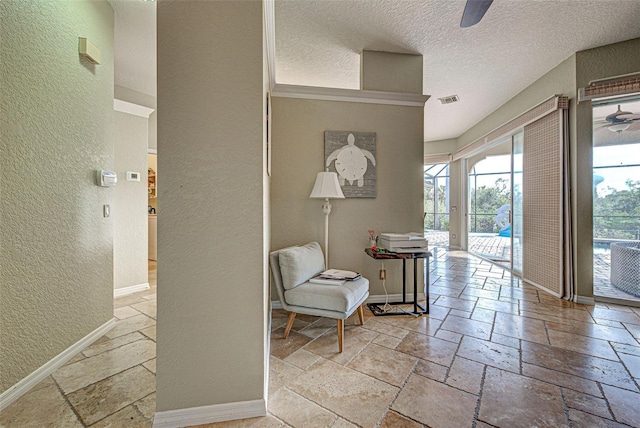 hall with visible vents, stone tile flooring, and baseboards