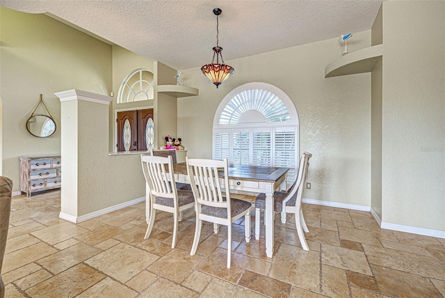 dining space featuring stone tile floors, baseboards, and a textured ceiling