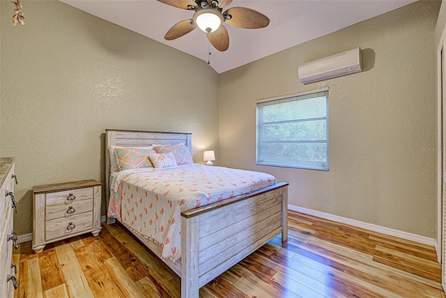 bedroom featuring baseboards, a ceiling fan, a wall unit AC, lofted ceiling, and light wood-style flooring