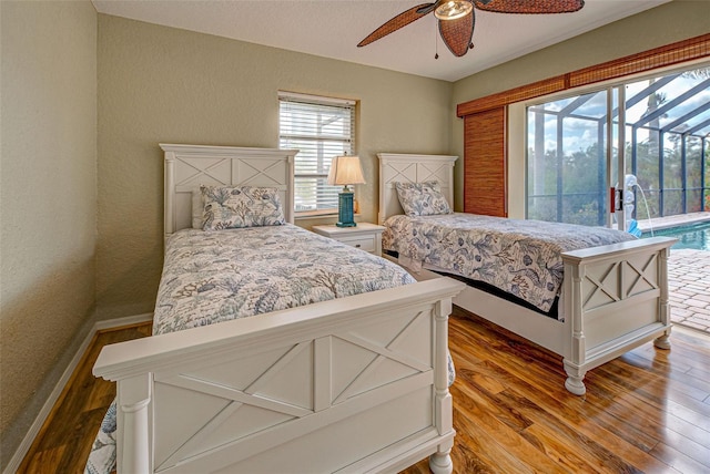 bedroom with wood finished floors, a ceiling fan, a sunroom, baseboards, and access to outside