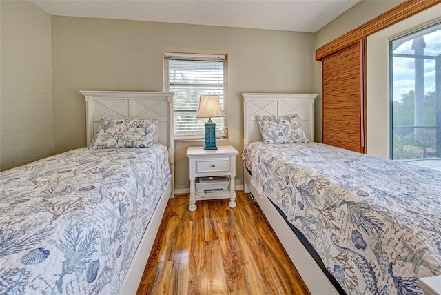 bedroom with multiple windows, light wood-style flooring, and baseboards