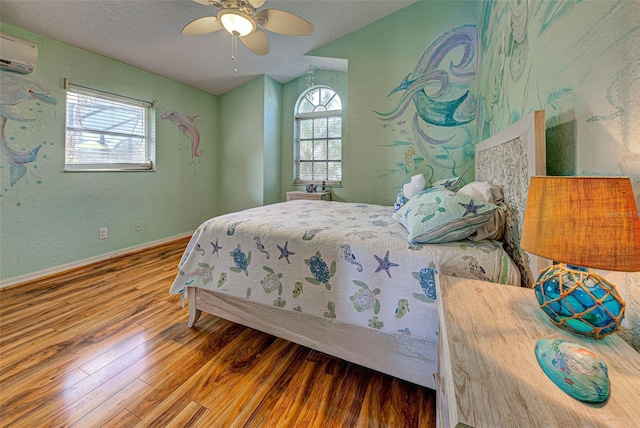 bedroom featuring an AC wall unit, multiple windows, wood finished floors, and baseboards